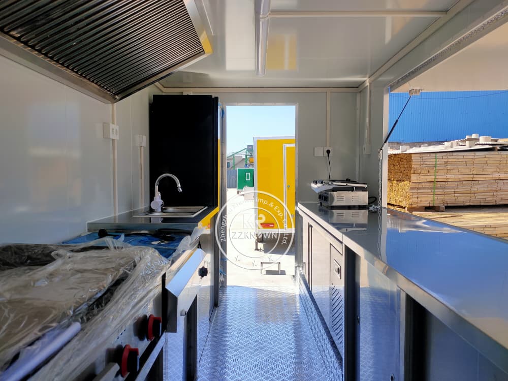 Fully stocked sandwich trailer kitchen showing cold storage, griddle, and exhaust system
