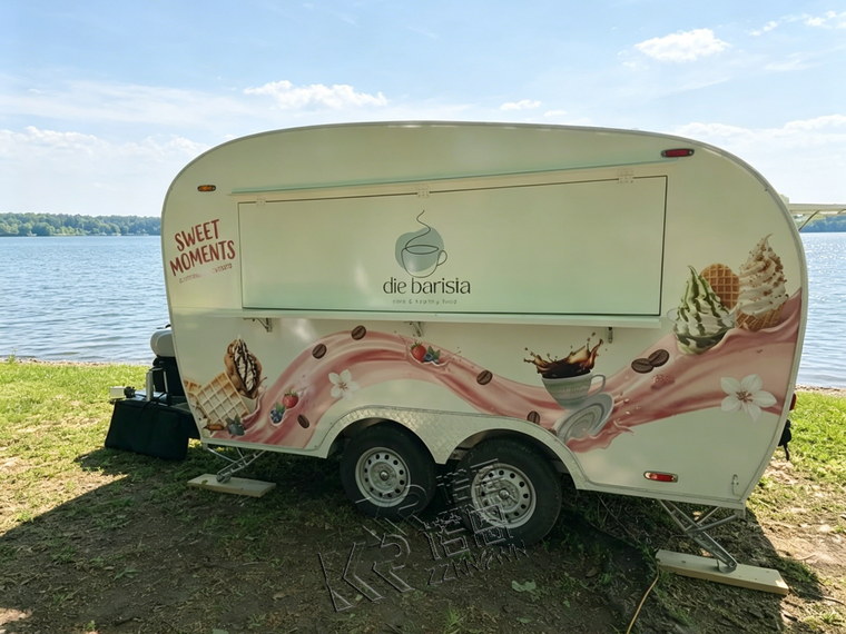 Double-axle curved food trailer beside a lake