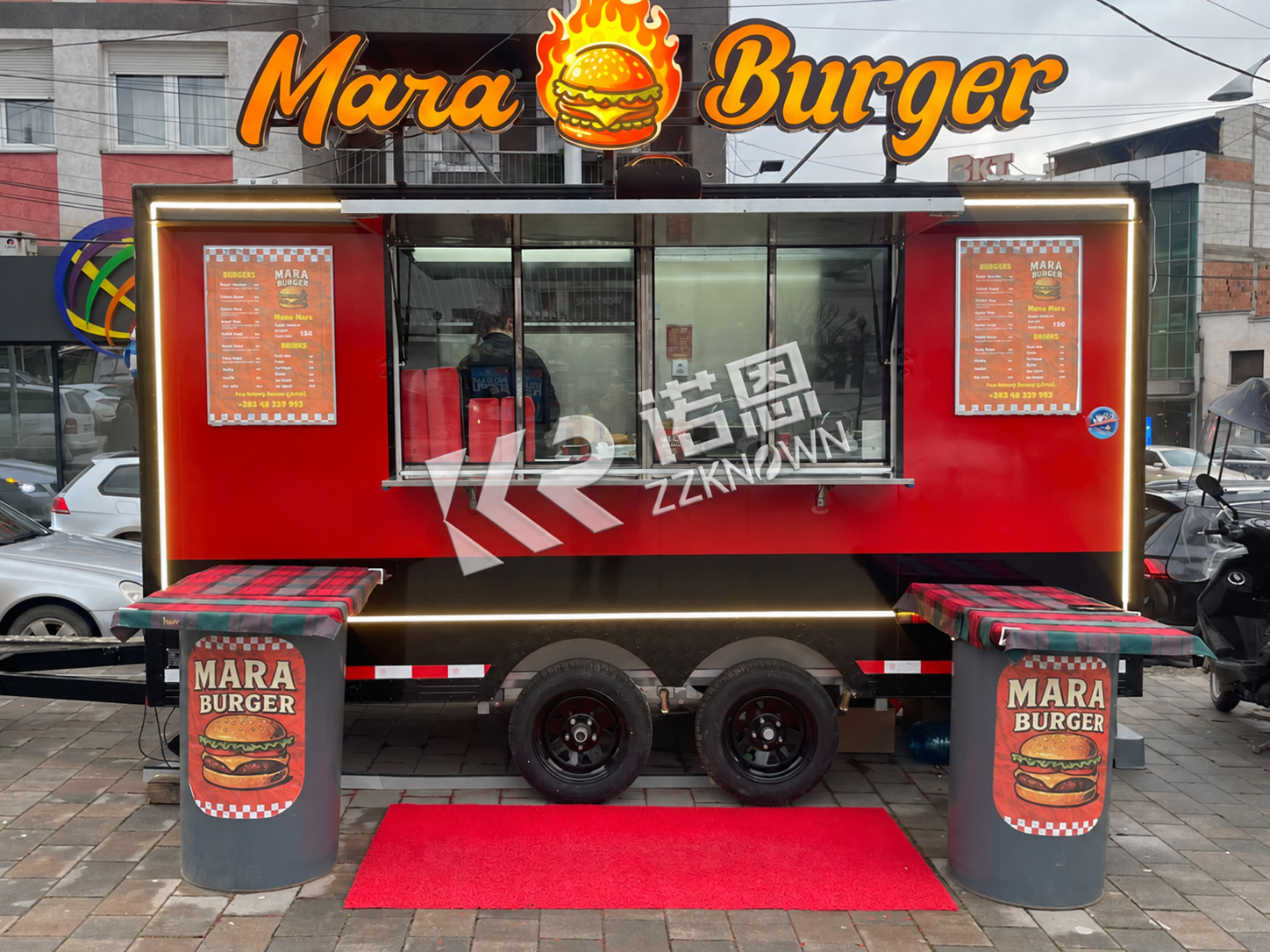 Red and black dual-axle burger trailer prepared for customer service